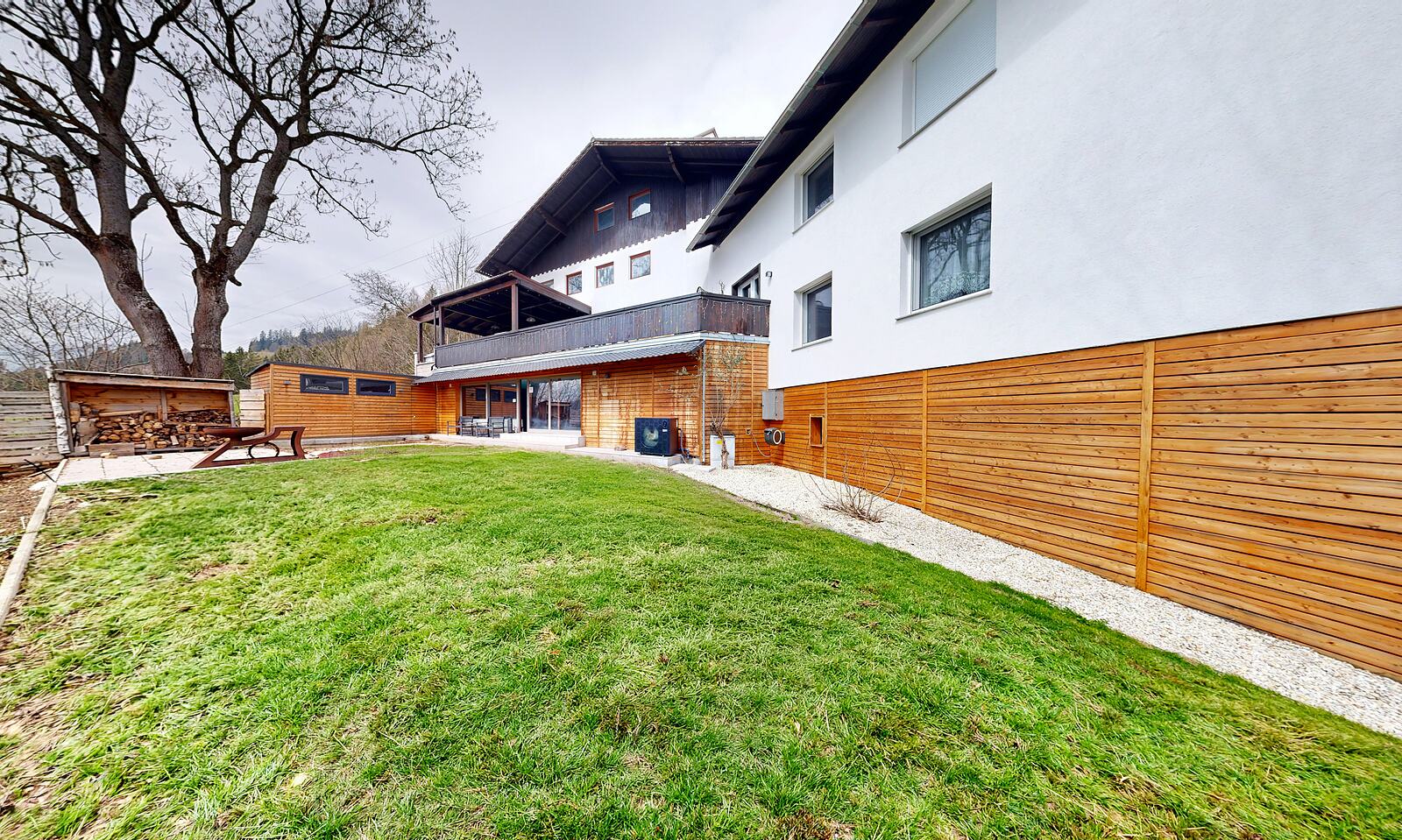 Villa E25 seen from its lawn, white walls under a dark gabled roof.