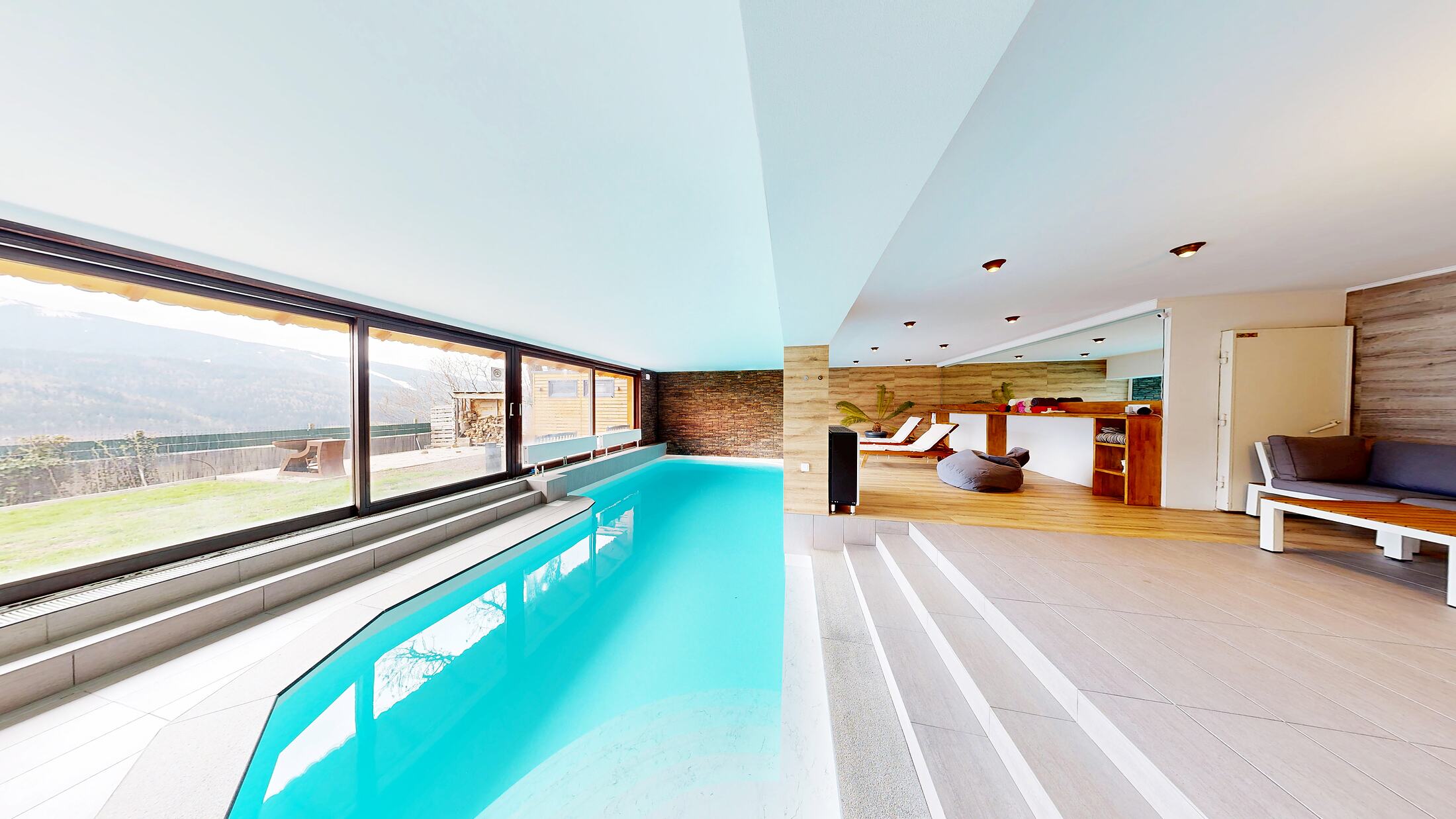The heated indoor pool at Villa E25 against a full-height wall of glass looking into the valley.